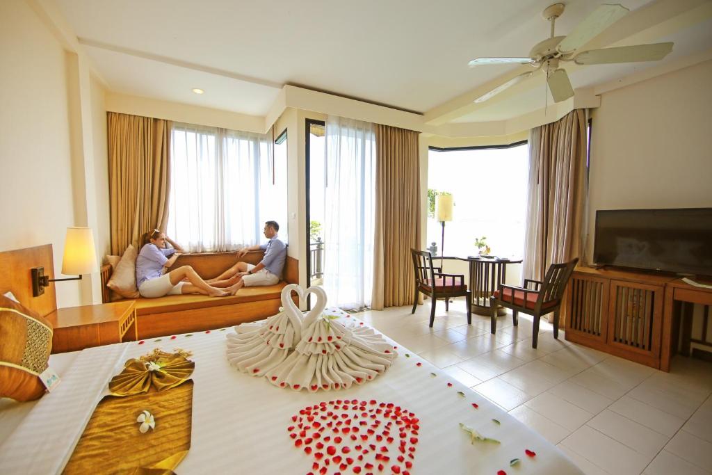 a man and woman sitting on a couch in a living room at Supalai Scenic Bay Resort And Spa, SHA Extra Plus in Por Bay