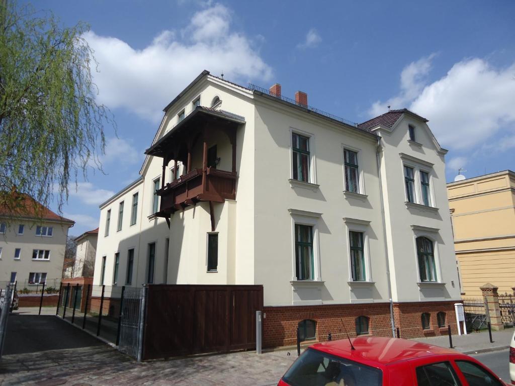 een wit gebouw met een balkon aan de zijkant bij PP Pension Potsdam in Potsdam