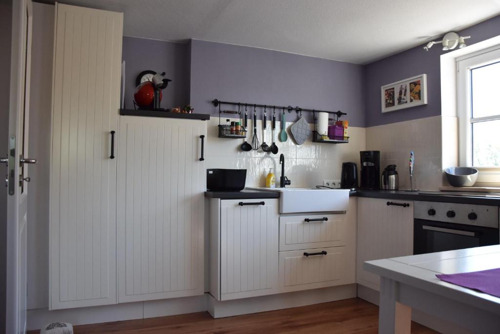 a kitchen with white cabinets and a sink at Ferienwohnung-Sonnenblume in Grube