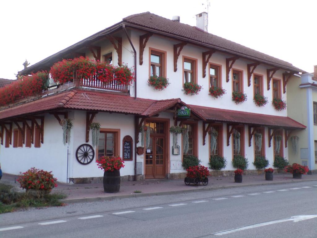 a white building with red flowers on a street at Penzion Restaurace u Helferů in Libuň