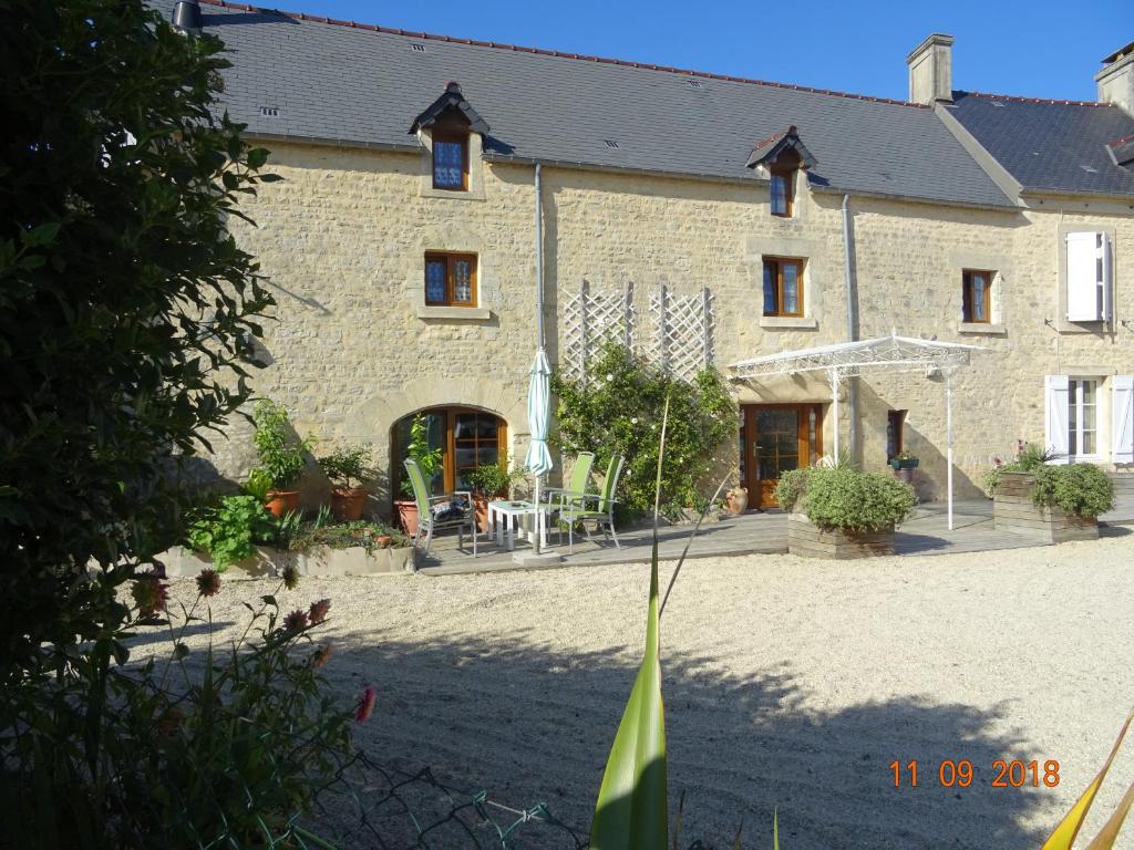 a large stone building with a courtyard in front of it at La ferme aux chats in Formigny