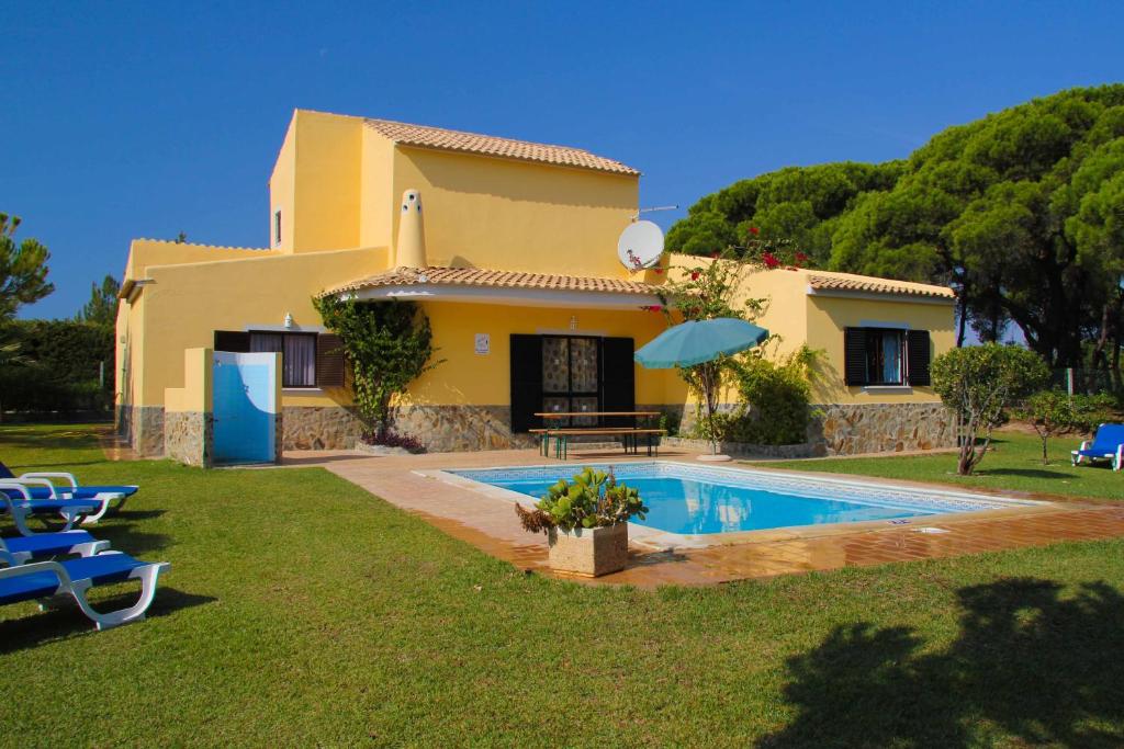 a villa with a swimming pool in front of a house at Quinta Vita - Vila Uva in Almancil