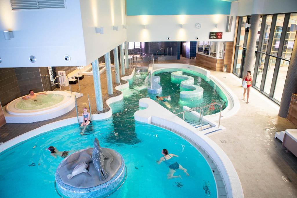 a pool in a building with people swimming in it at Finlandia Hotel Imatran Kylpylä Spa in Imatra