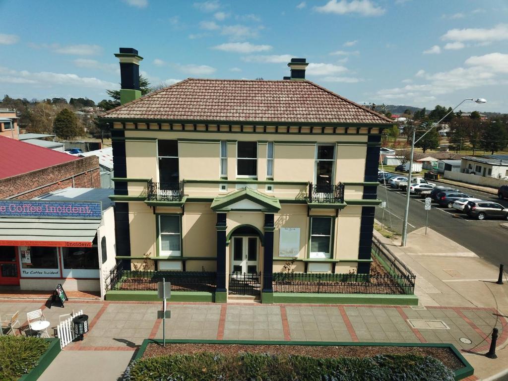 a yellow house with a red roof on a street at The Bank Guesthouse Glen Innes in Glen Innes