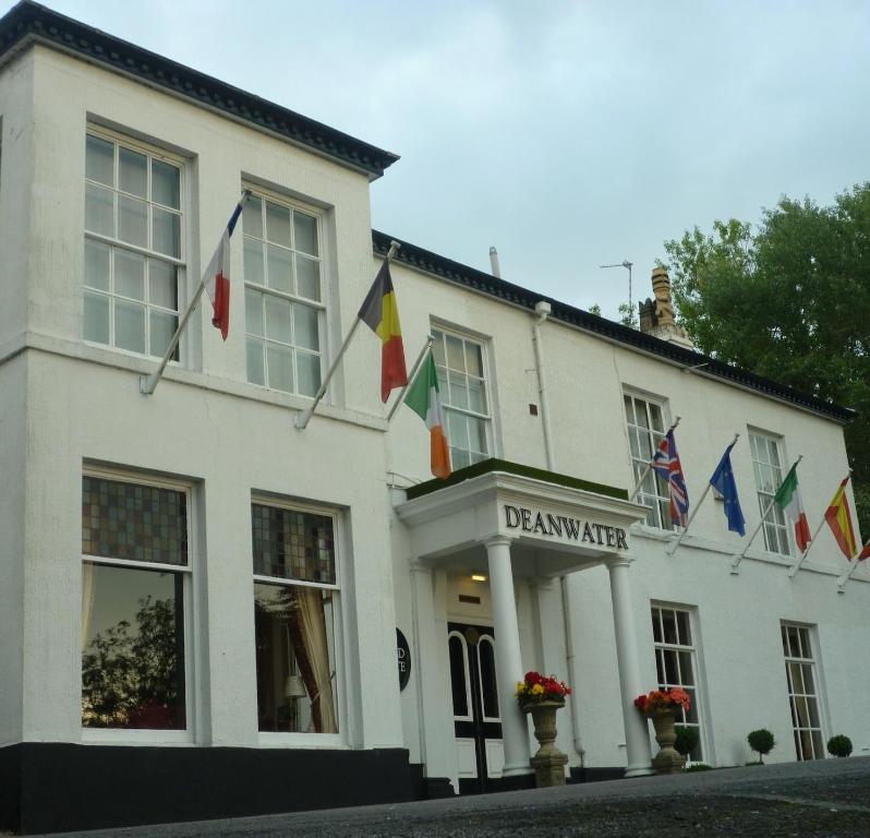 a white building with flags in front of it at Deanwater Hotel in Wilmslow