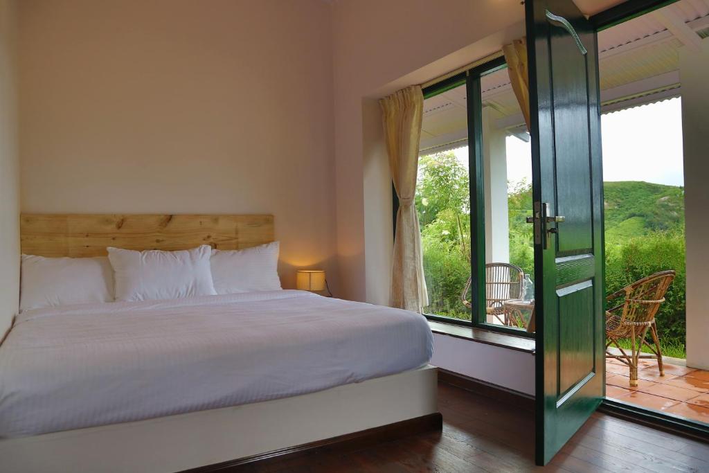 sypialnia z dużym łóżkiem i balkonem w obiekcie The Tamarillo w mieście Utakamand