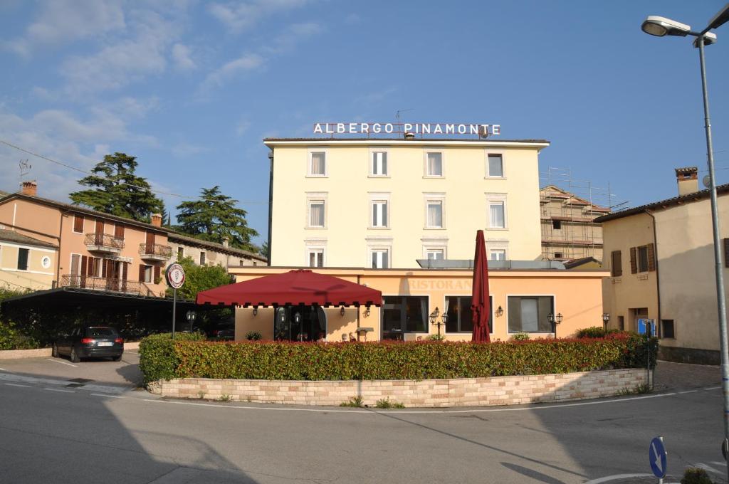 een wit gebouw met een rode paraplu ervoor bij Hotel Pinamonte in Costermano