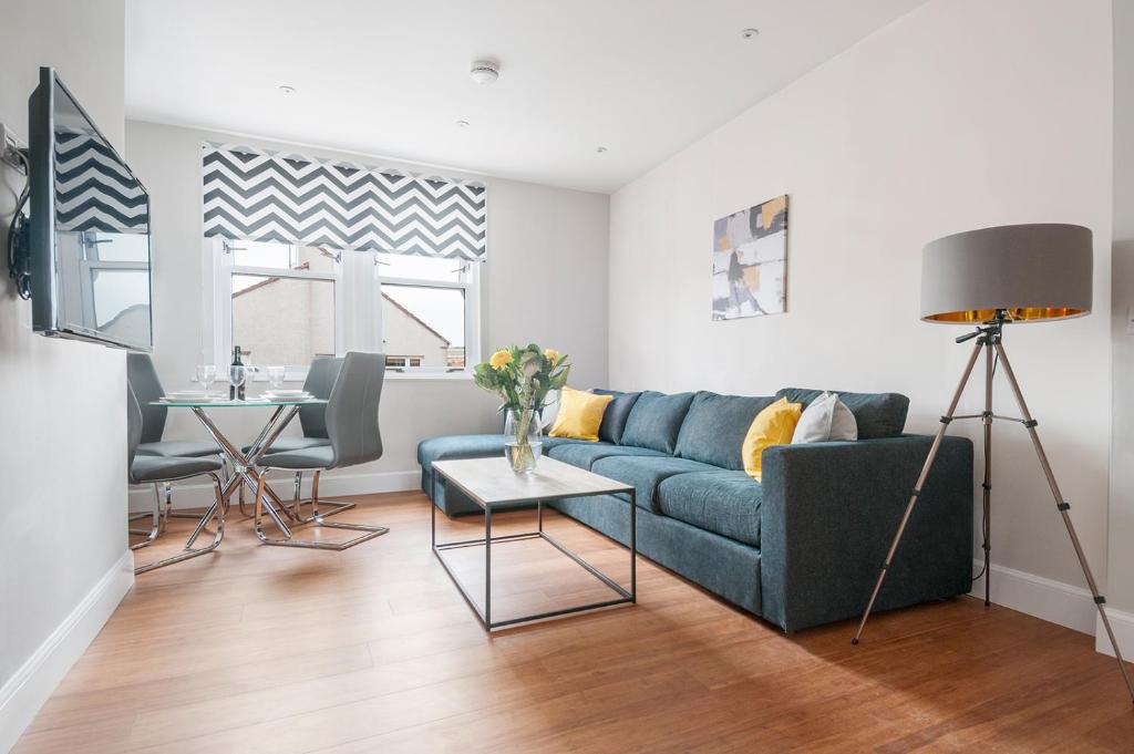 a living room with a blue couch and a table at Dalkeith Three Bed Two Bath Apartment in Dalkeith