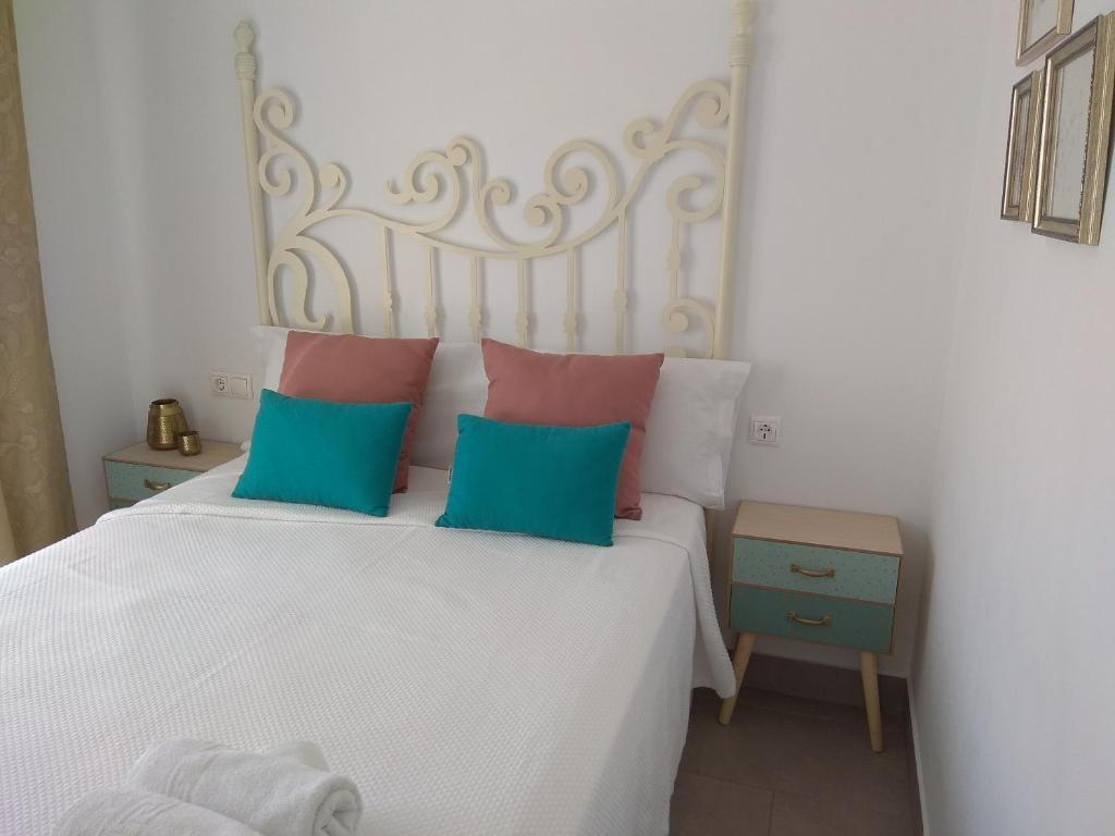 Un dormitorio con una cama blanca con almohadas azules y rosas en Piso en Córdoba Emili´s House, en Córdoba