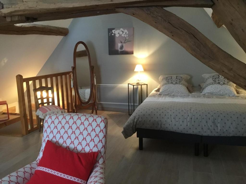 a bedroom with a bed and a chair at Aux Cornettes in Beaune