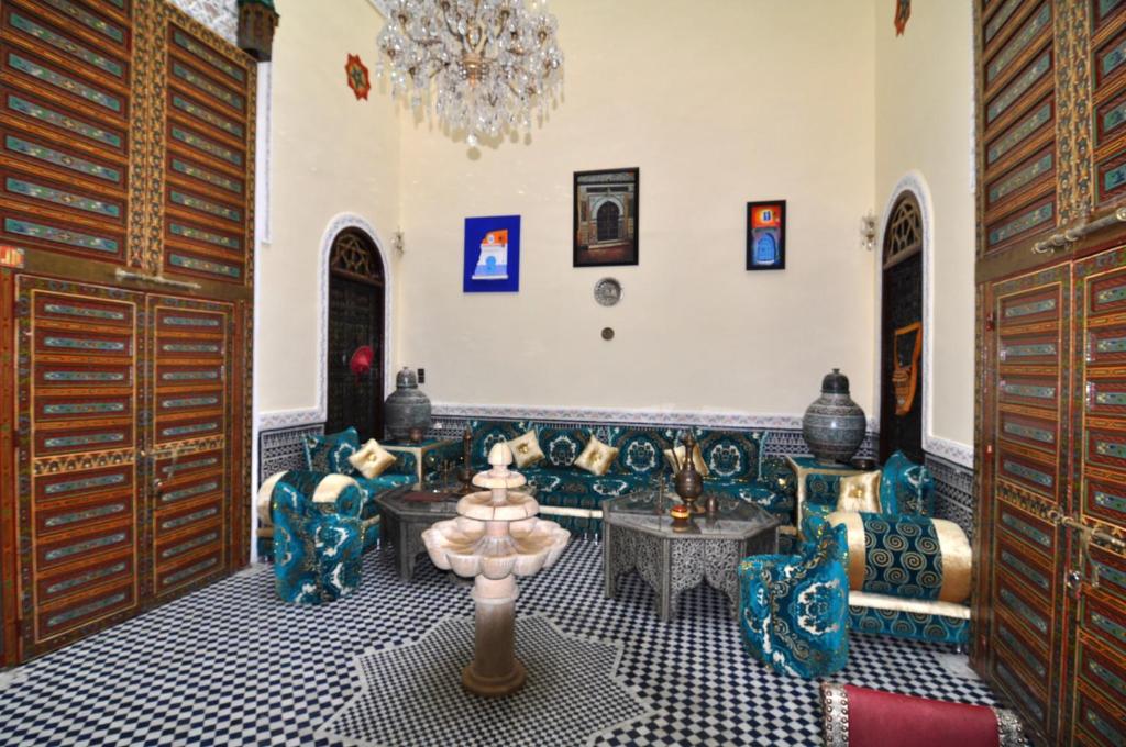 sala de estar con sofá, sillas y lámpara de araña en Riad Khouloud, en Fez
