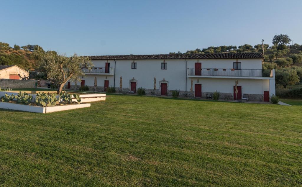 a large white house with a large grass field at Agriturismo di Serragiumenta in Altomonte