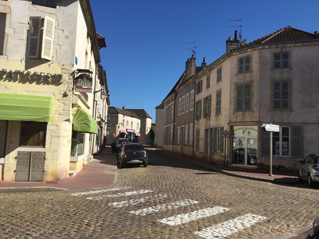 a car driving down a cobblestone street with buildings at Aux Cornettes in Beaune