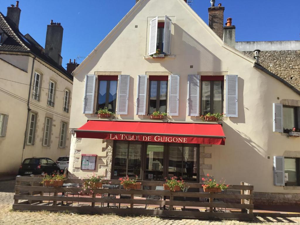 a white building with a red awning on it at Aux Cornettes in Beaune