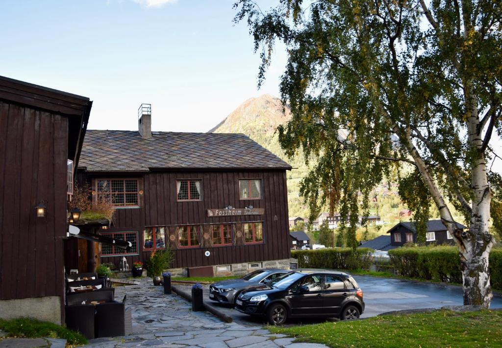 a house with two cars parked in front of it at Fossheim Hotel Lom in Lom