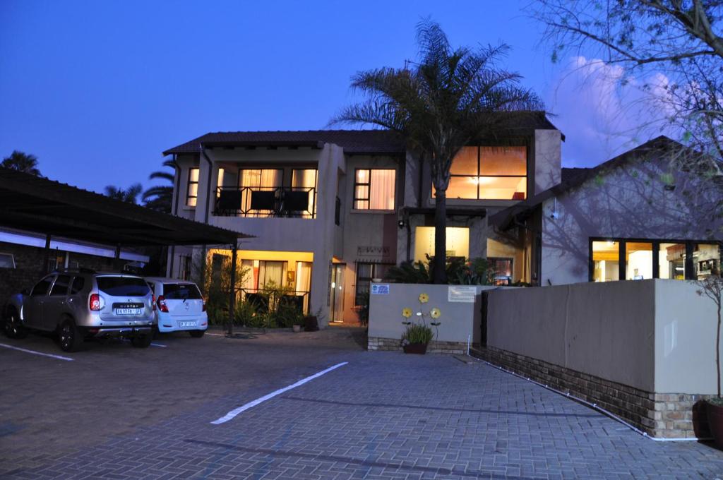 una casa con un coche aparcado en un estacionamiento en Woodpecker's Inn Guest House, en Kempton Park