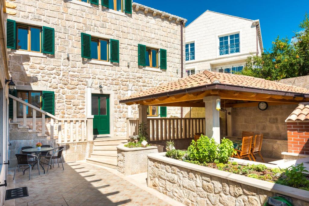 ein Steinhaus mit einer Terrasse mit einem Tisch und Stühlen in der Unterkunft Apartments Villa Kulish in Cavtat
