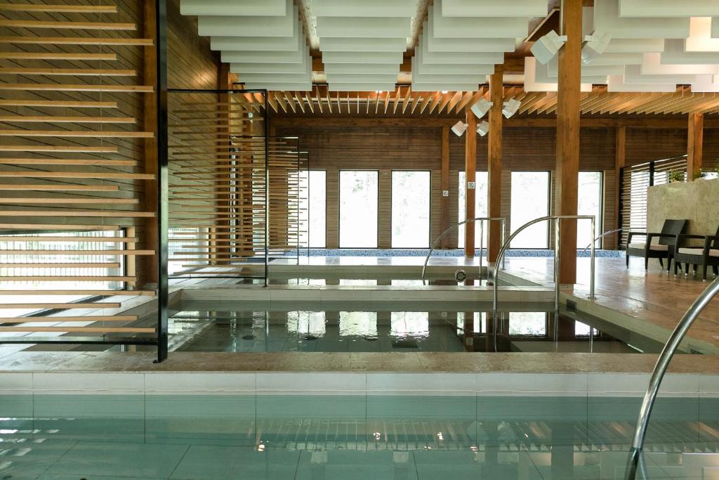 uma piscina numa casa com pisos de vidro e tectos de madeira em Kubija Hotel and NatureSpa em Võru