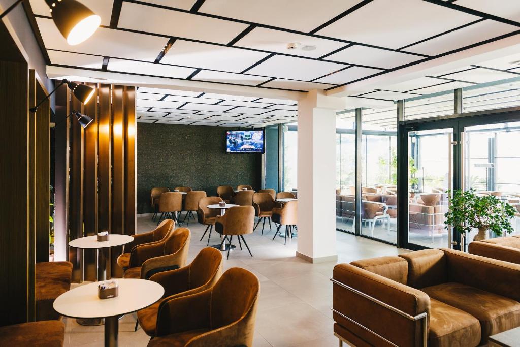 una sala de espera con mesas, sillas y ventanas en Hotel Egnatia, en Tirana