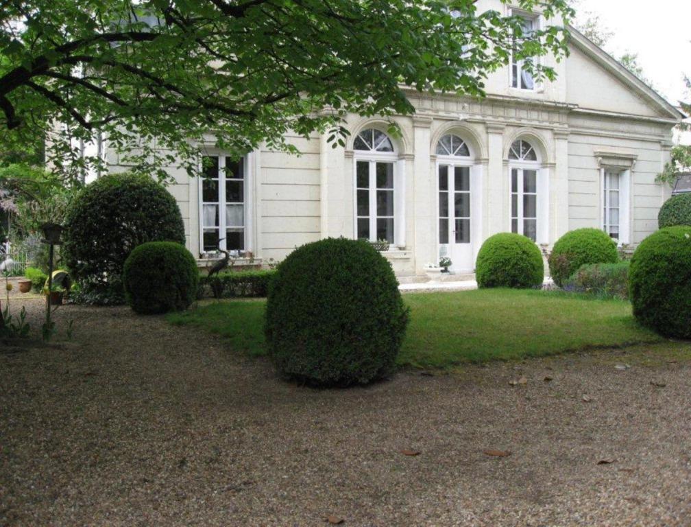 une maison blanche avec des buissons devant elle dans l'établissement Le Belvédère, Studio, à Bléré