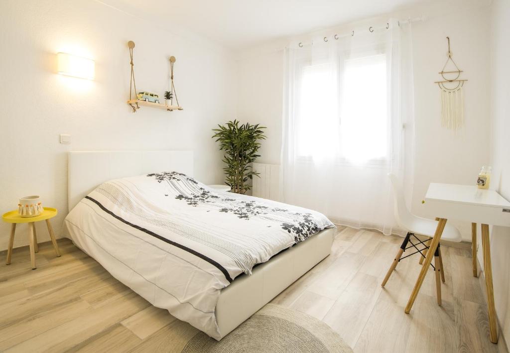 カネ・アン・ルシヨンにある"COSY" Appartement confort de 50m2 à 150m de la Mer et du Centre ville, parking gratuitの白いベッドルーム(ベッド1台、デスク付)