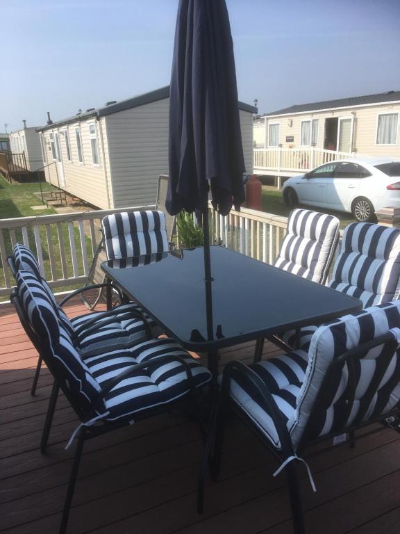 a table and chairs with an umbrella on a deck at Golden palm resort skegness in Chapel Saint Leonards