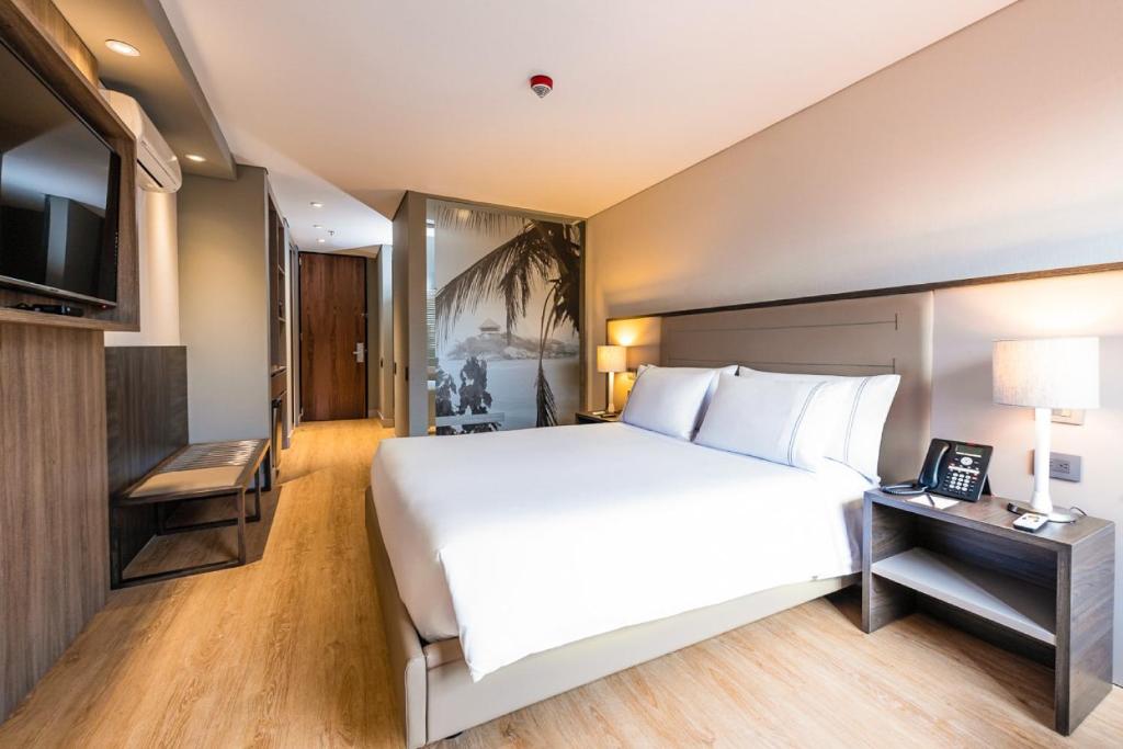 a bedroom with a large white bed and a television at Hotel Habitel Prime in Bogotá