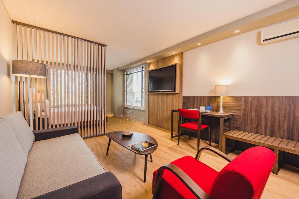 ein Wohnzimmer mit einem Sofa und roten Stühlen in der Unterkunft Hotel Habitel Prime in Bogotá