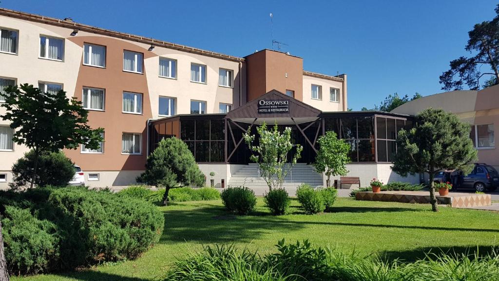 un hôtel avec une pelouse devant un bâtiment dans l'établissement Hotel Ossowski, à Swarzędz