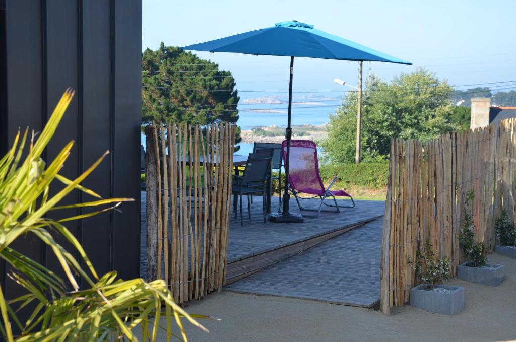 a wooden deck with a table and an umbrella at Bellevues-Sur-Mer, à 100 m de la plage in Trévou-Tréguignec