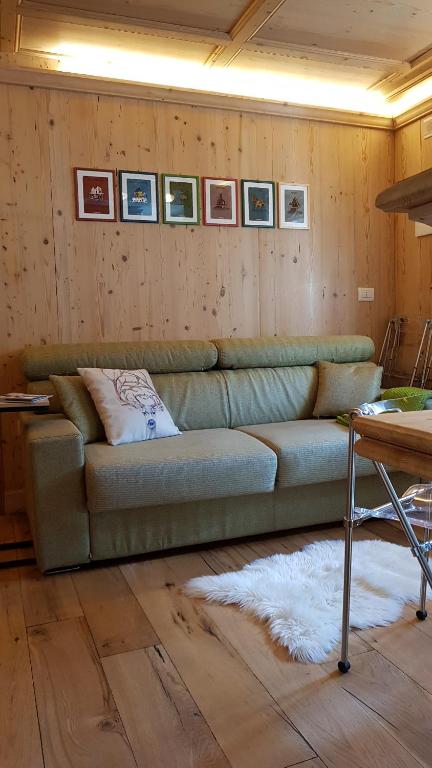 a living room with a green couch and pictures on the wall at Bilocale Ristrutturato in Madesimo