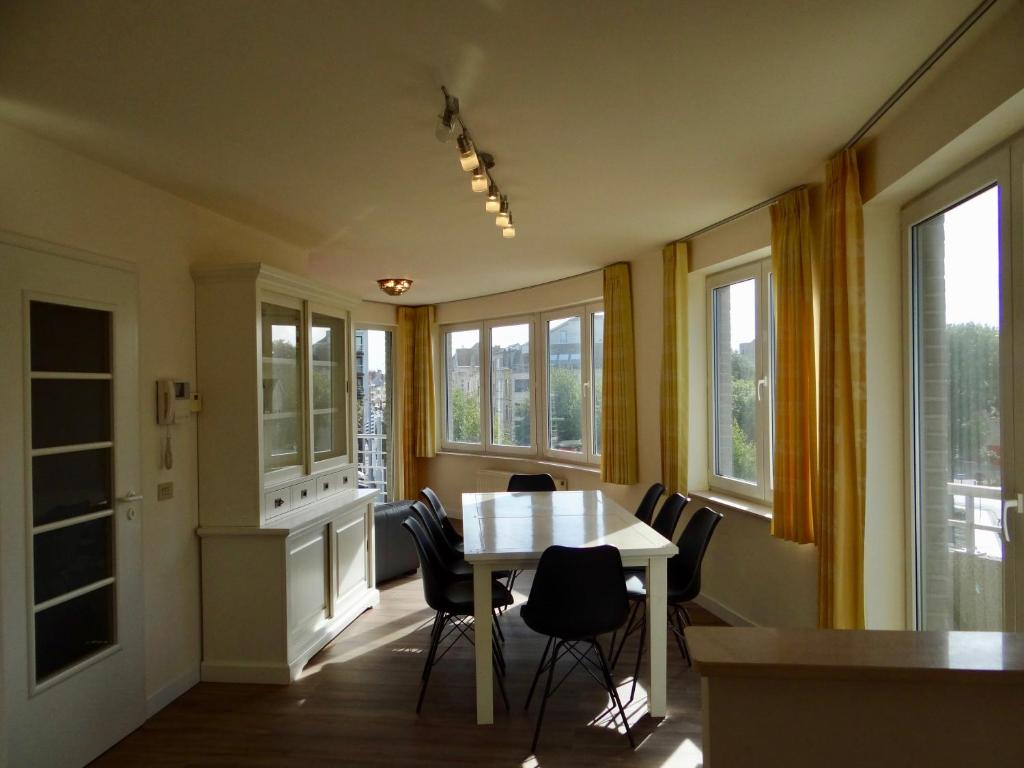 a dining room with a table and chairs and windows at Holiday Cottages Blankenberge in Blankenberge