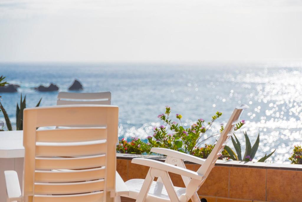 2 sillas y una mesa en un balcón con vistas al océano en Exclusive frontline one bedroom apartment, en Puerto de Santiago