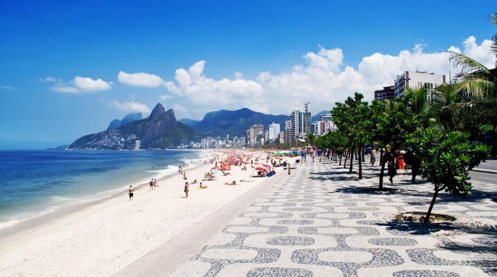 a beach with a crowd of people and the ocean at CLH Suites Domingos Ferreira in Rio de Janeiro