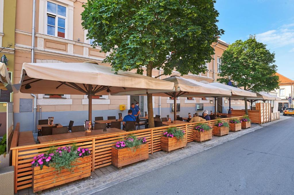 a restaurant with tables and umbrellas on a street at Hotel Slovenj Gradec in Slovenj Gradec