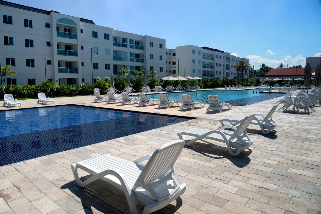 a group of lounge chairs next to a swimming pool at Palm Village Acqua in Porto De Galinhas