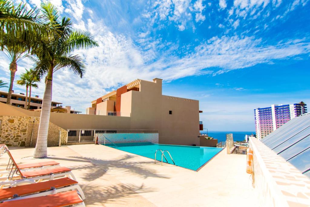 uma piscina com palmeiras e um edifício em Paraiso Pool and Sea View - TENESOL RENTALS em Adeje