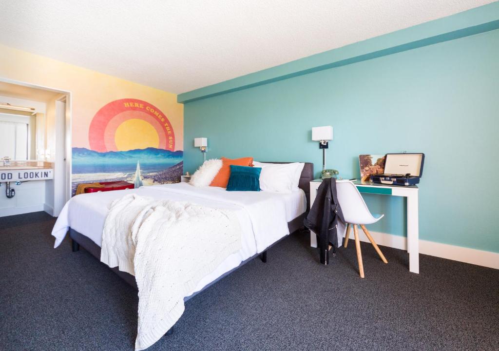 a bedroom with a large bed with a painting on the wall at Rambler Motel in Chula Vista