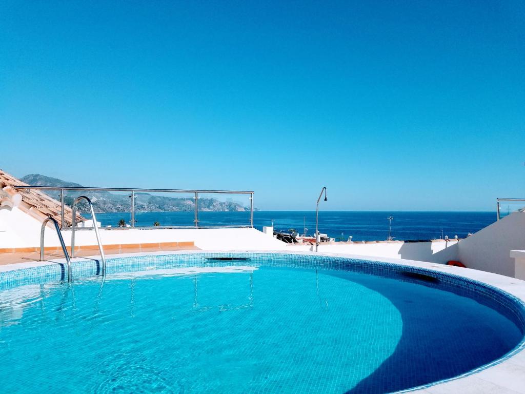 una piscina con el océano al fondo en Maravilloso apartamento, en Nerja