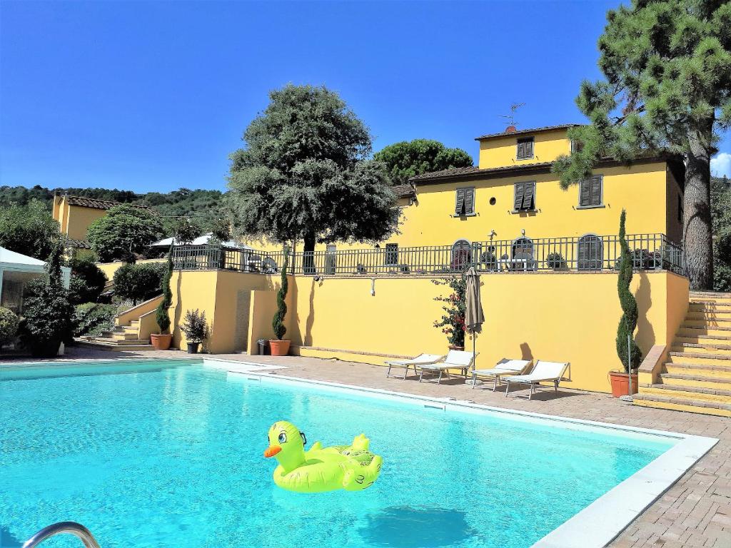 two rubber duckyids in a swimming pool next to a yellow building at Agriturismo Villa Bracali in Serravalle Pistoiese