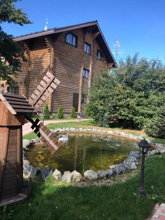 a pond in front of a log house at Diva Mini-hotel in Podolsk