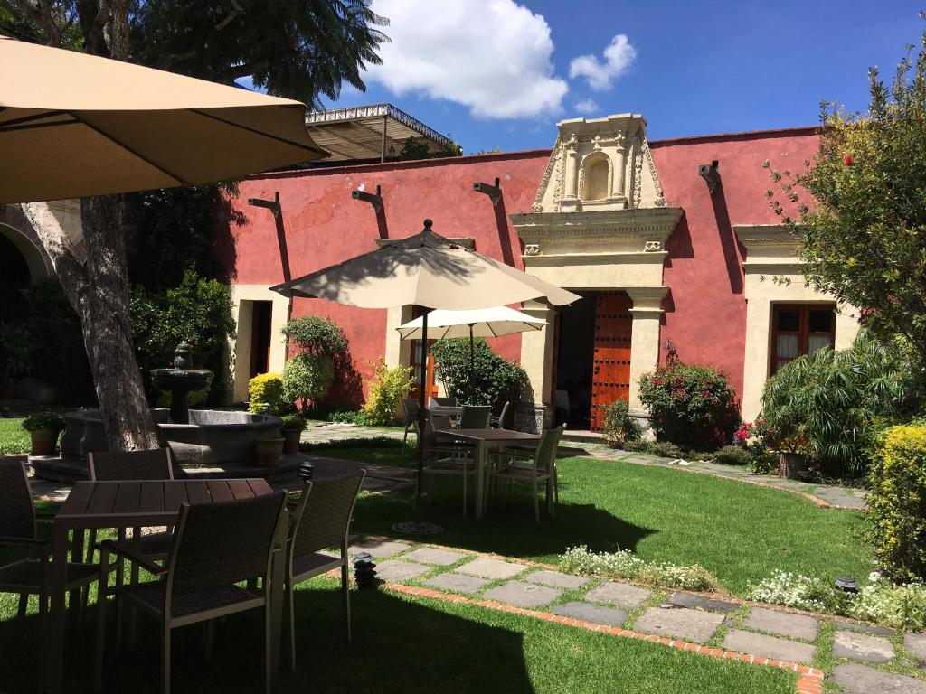 un patio avec des tables et des parasols en face d'un bâtiment dans l'établissement Quinta Luna, à Cholula