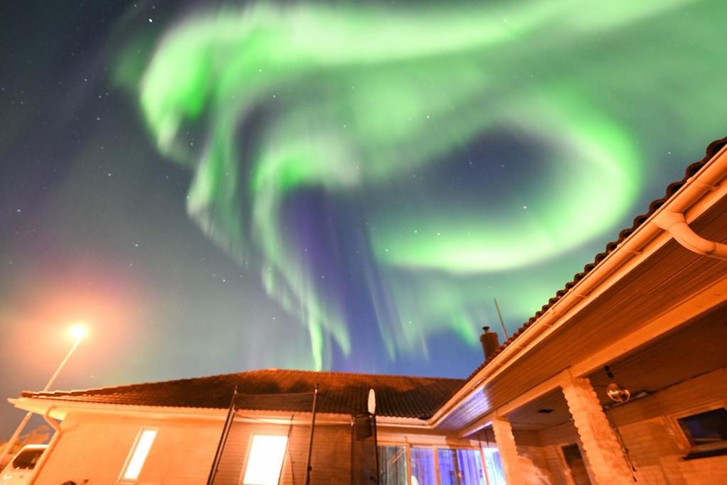 obraz zorzy polarnej na niebie nad domem w obiekcie The Northern Light Apartment w mieście Jukkasjärvi