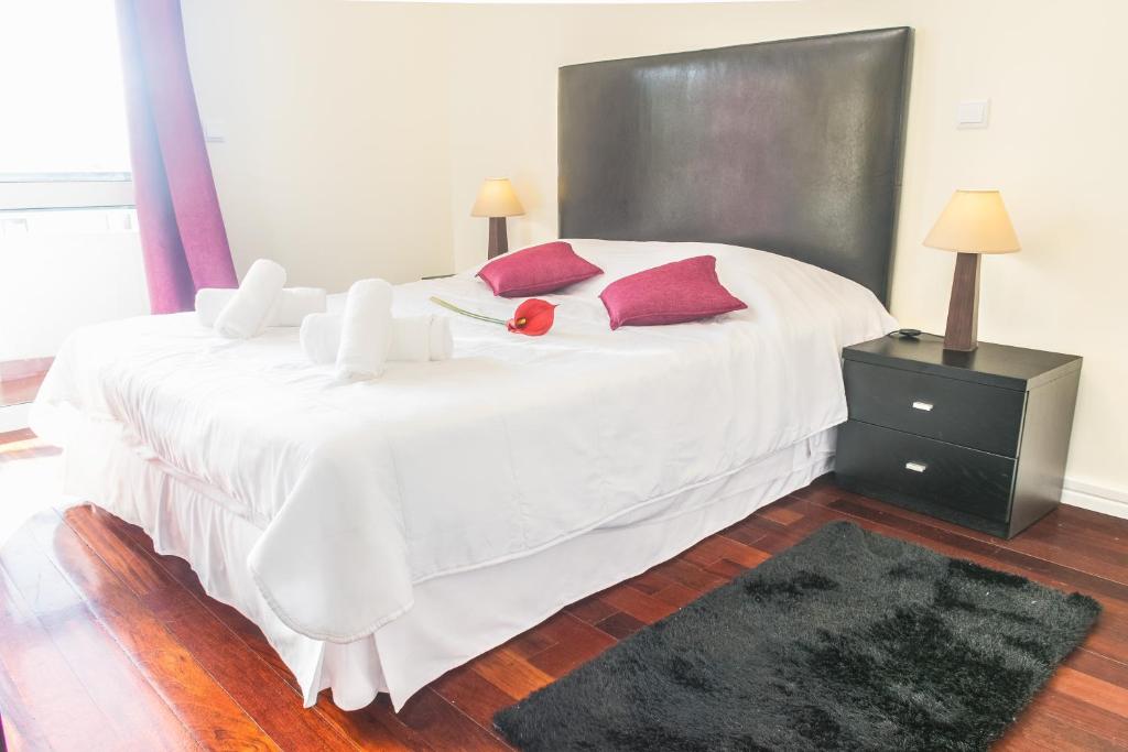 een slaapkamer met een groot wit bed met rode kussens bij Arcadas Cozy Apartments - AU in Funchal