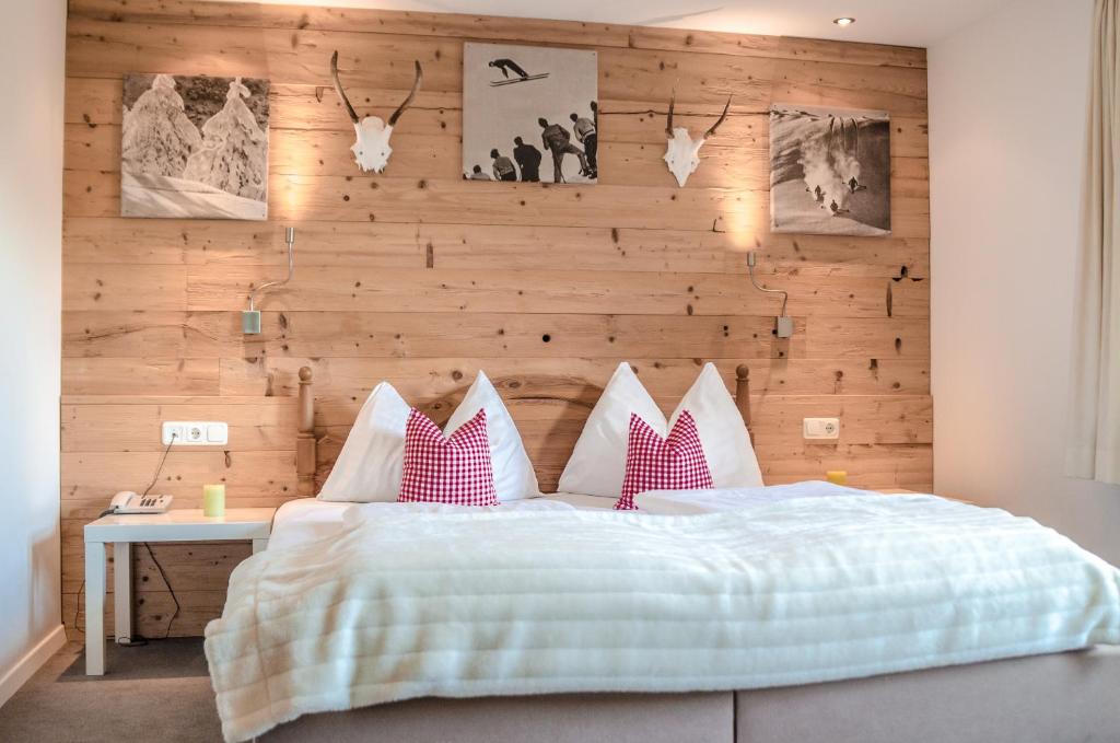 a bedroom with a bed with a wooden wall at Hotel Unterbrunn Apartments & Gästehaus in Neukirchen am Großvenediger