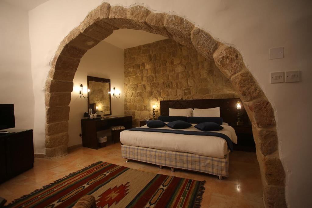 a bedroom with a large bed with a stone wall at The Old Village Hotel & Resort in Wadi Musa