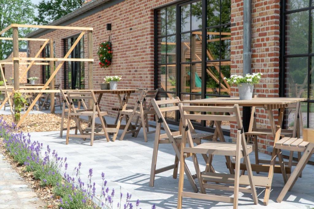 een groep tafels en stoelen voor een bakstenen gebouw bij De Worfthoeve in Geel