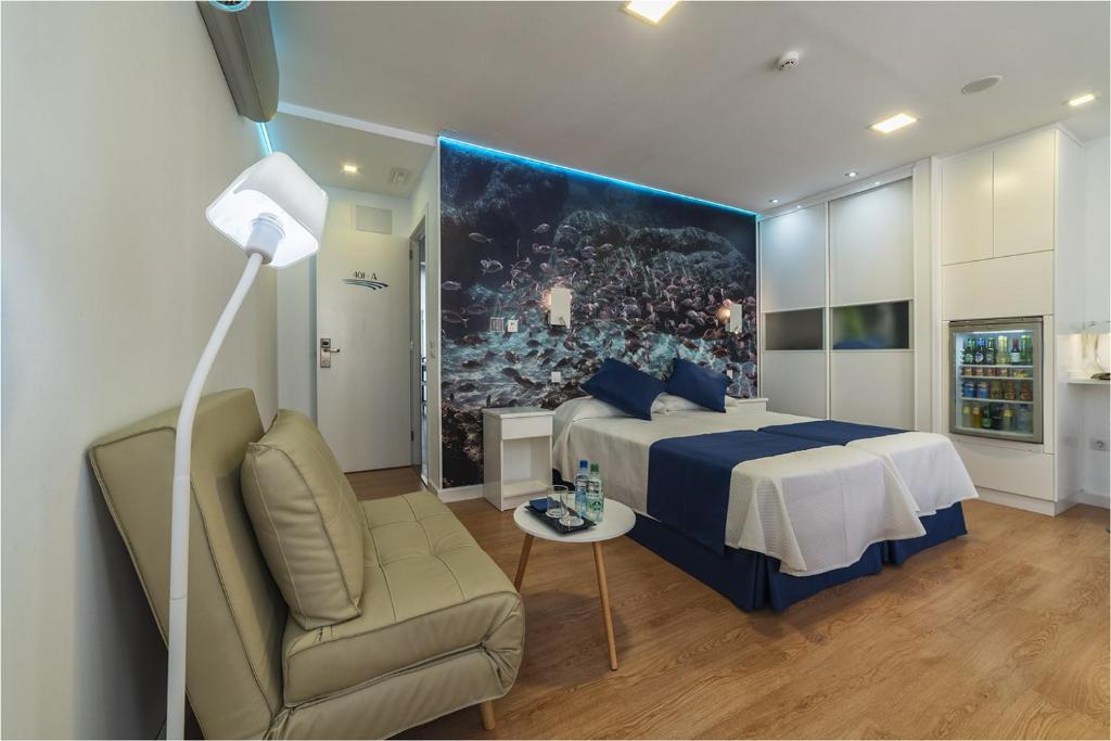 a bedroom with a bed and a couch and a chair at Hotel Ciudad del Mar in Las Palmas de Gran Canaria