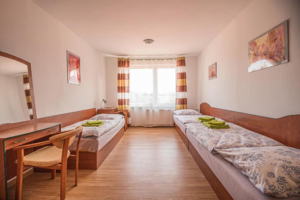リプトフスキー・ハラードクにあるHýbadloのベッド2台、デスク、鏡が備わる客室です。