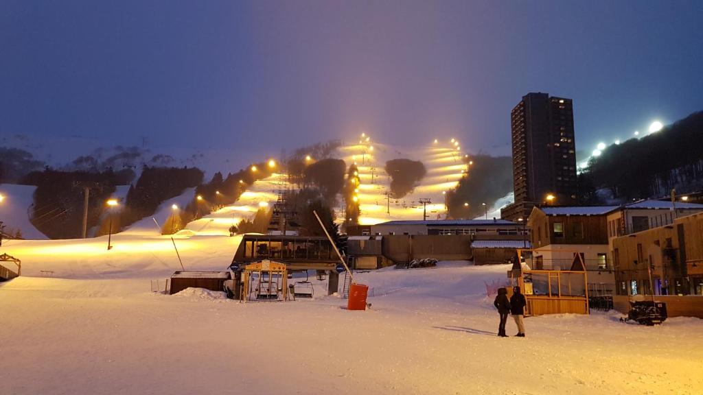 un grupo de personas de pie en la nieve por la noche en Studio-cabine au pied des pistes à Super Besse en Super Besse